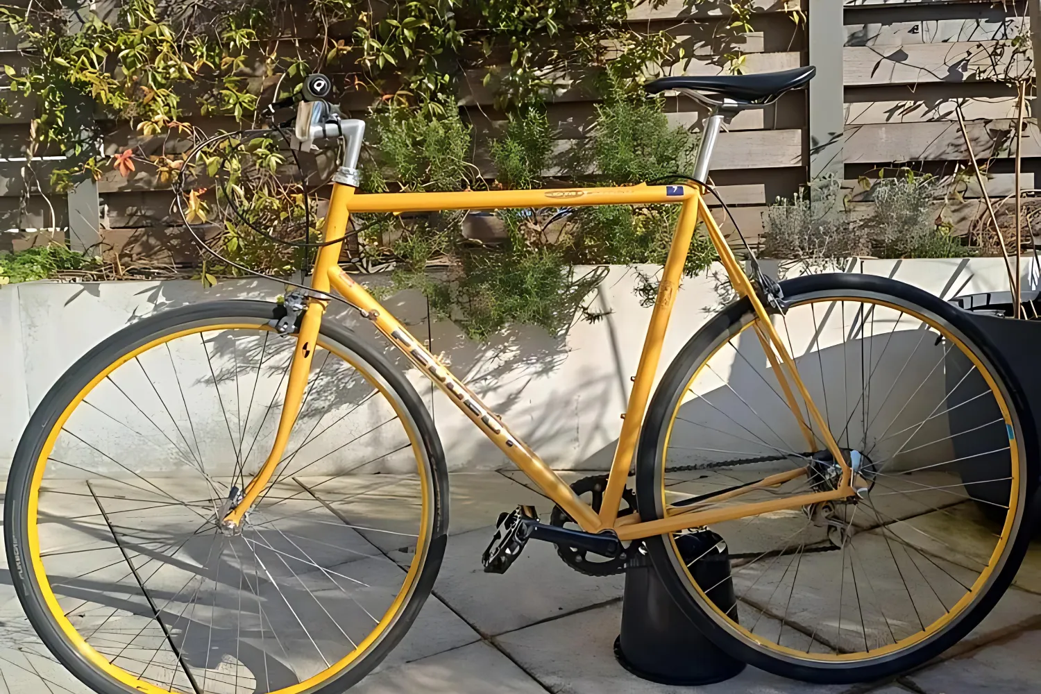 Vélo de route vintage jaune d'occasion posé contre un muret fleuri — acheter un vélo d'occasion à Paris — The Rolling Steph