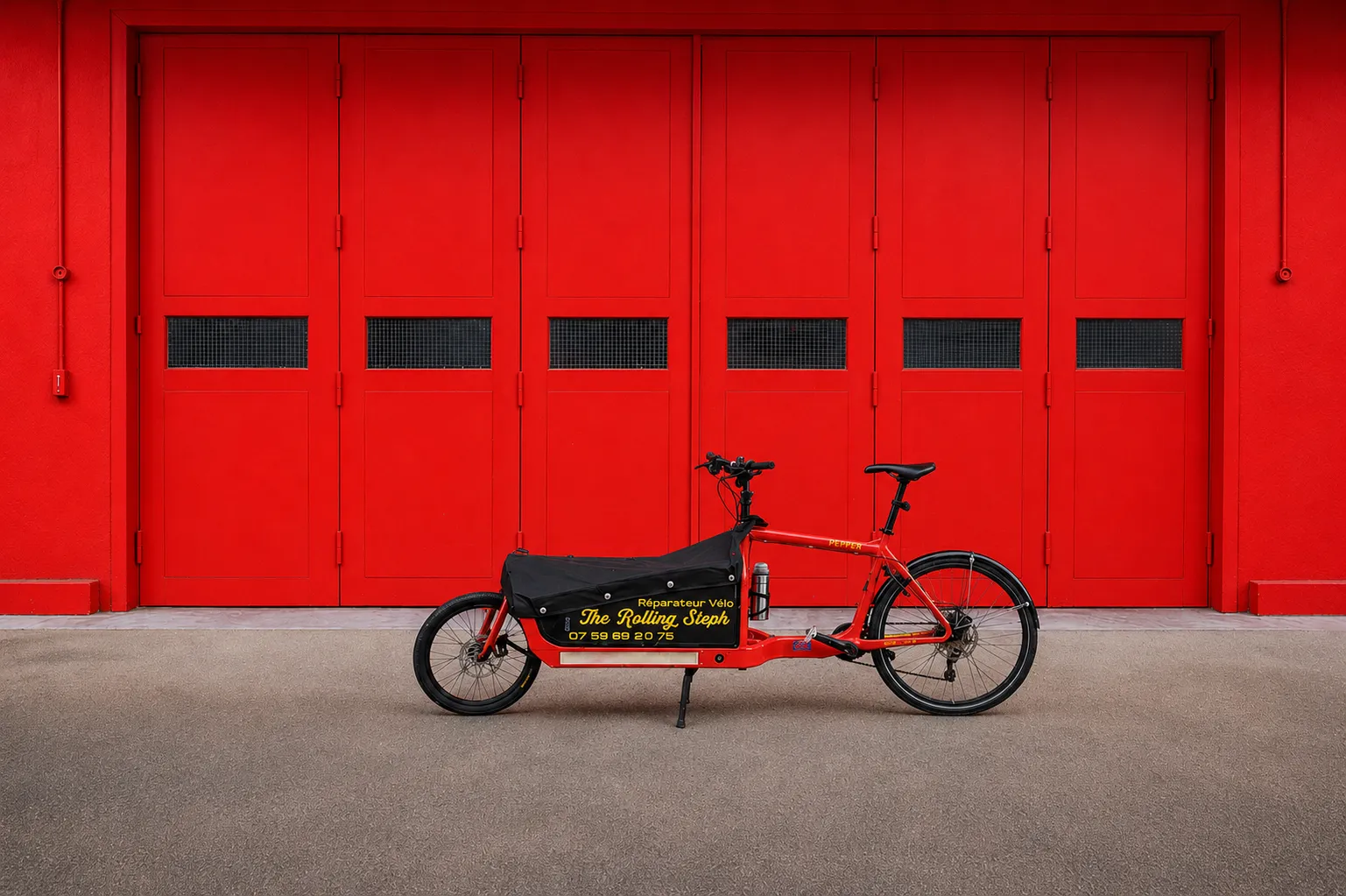 Pepper, le vélo-cargo atelier de The Rolling Steph, garé devant des portes rouges - The Rolling Steph