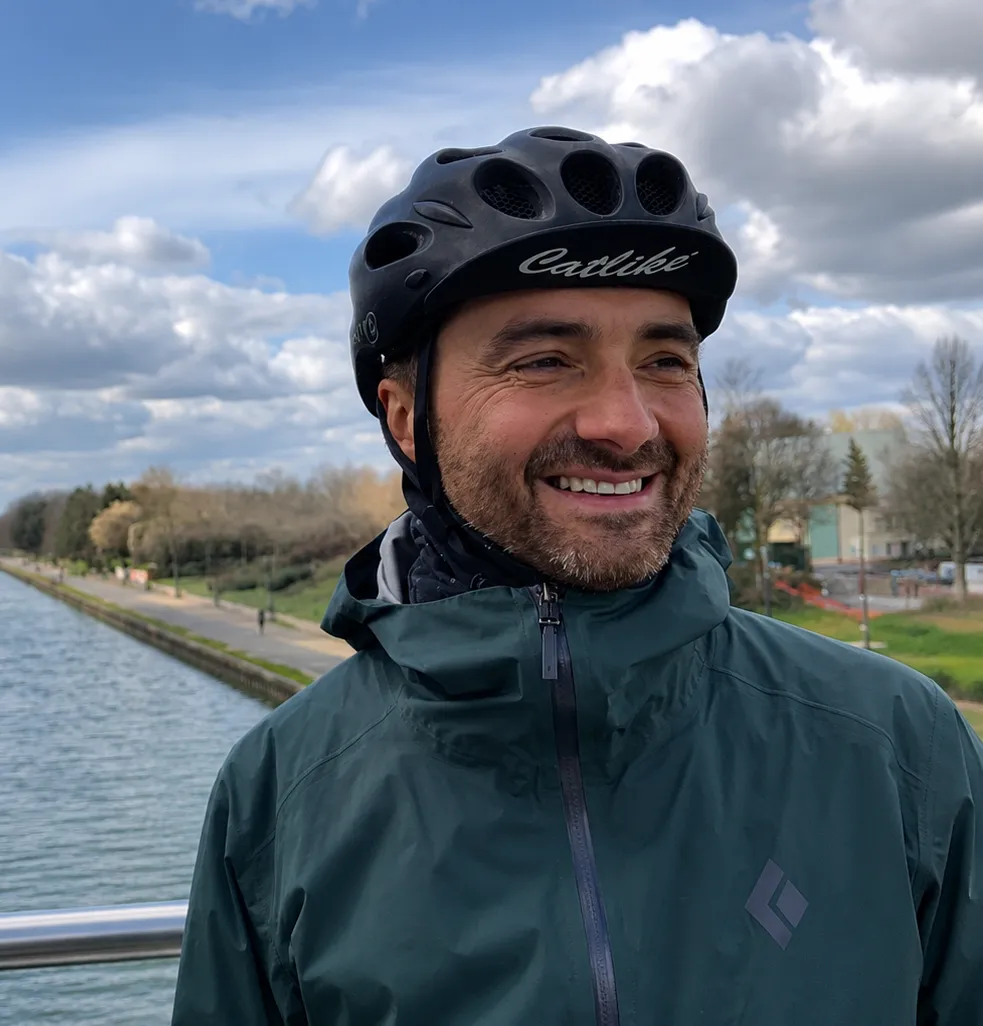 Steph, mécanicien vélo itinérant, casqué et souriant au bord du canal