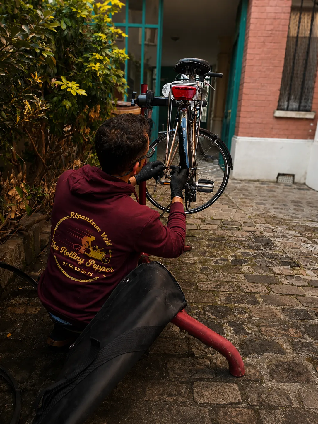 Steph réparant un vélo sur des pavés parisiens lors d'une intervention sur les freins - The Rolling Steph