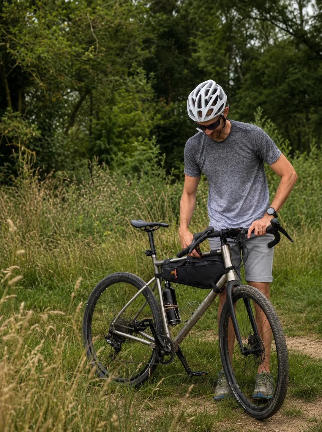 Cycliste avec un vélo gravel dans l'herbe, équipé pour les sorties - The Rolling Steph